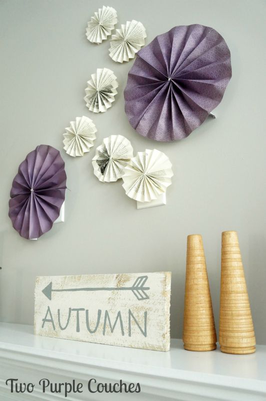 Light and natural wood tones and book pages paired with purples create a bright and non-traditional Fall Mantel. via www.twopurplecouches.com