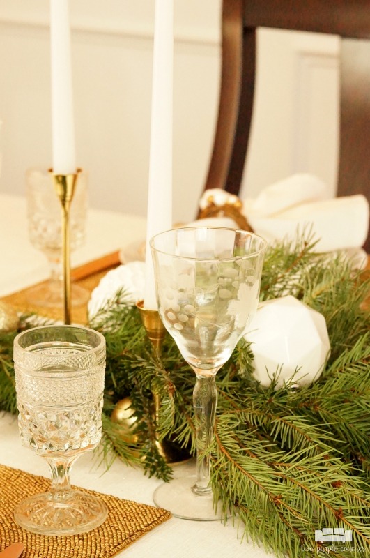 Beautiful holiday table idea! Use fresh, natural greenery and gold or brass candlesticks to create this simple yet elegant DIY evergreen Christmas tablescape. 