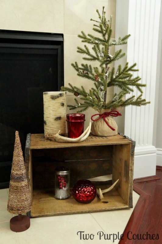 Repurpose a weathered beer crate to display trees, candles, and antlers for rustic Christmas decor.