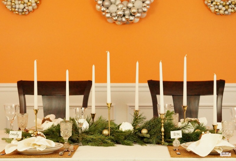 Beautiful holiday table idea! Use fresh, natural greenery and gold or brass candlesticks to create this simple yet elegant DIY evergreen Christmas tablescape. 