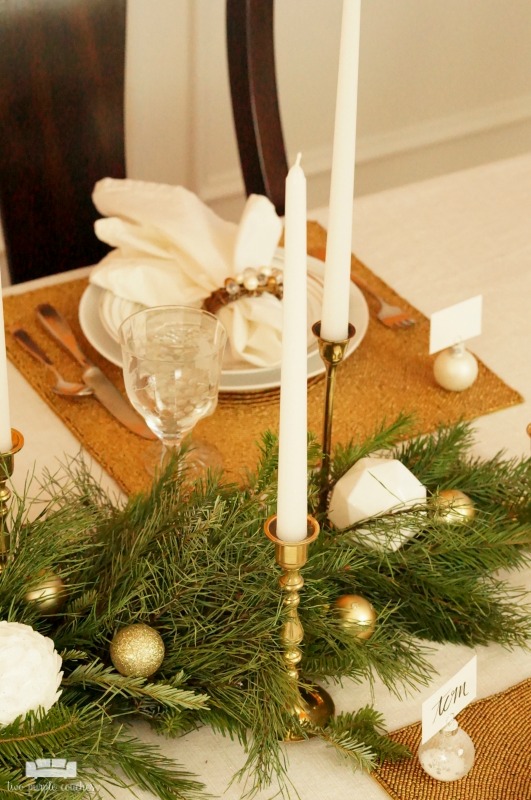 Beautiful holiday table idea! Use fresh, natural greenery and gold or brass candlesticks to create this simple yet elegant DIY evergreen Christmas tablescape. 